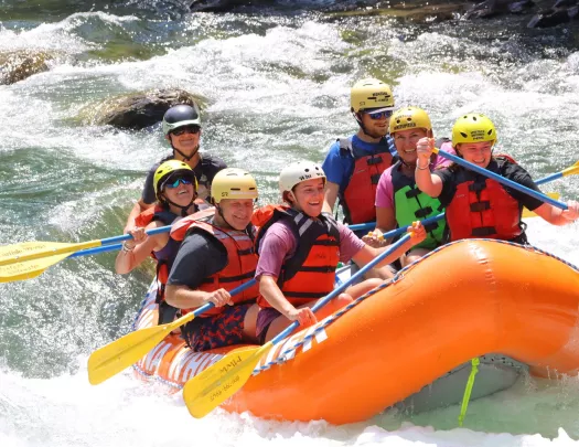 Group of men and women on an orange, inflatable raft in a river