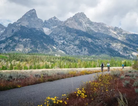 Three people biking with the Tetons in the background