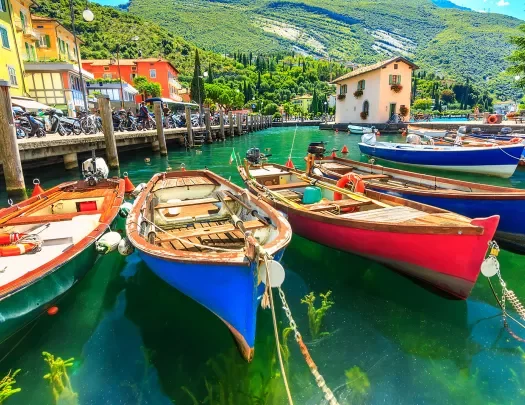 Multiple colorful boats tied to a dock by the ocean