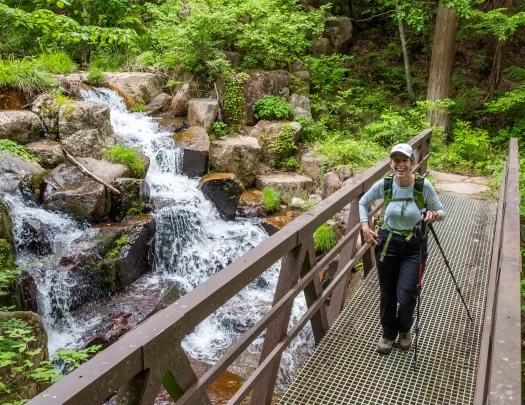 Woman standing on a bridge in front of a waterfall