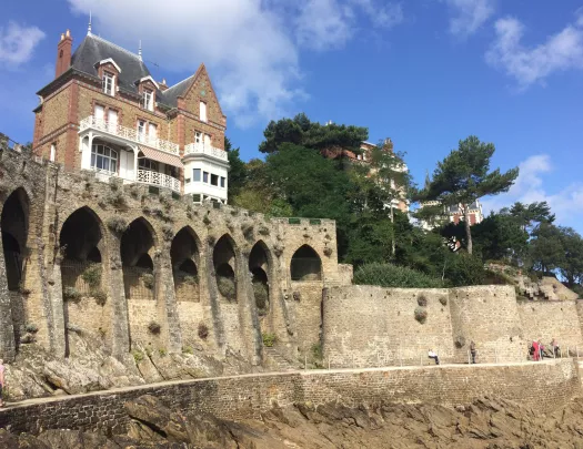 Large house on top of stone castle ruins with a stone pathway on the ground level