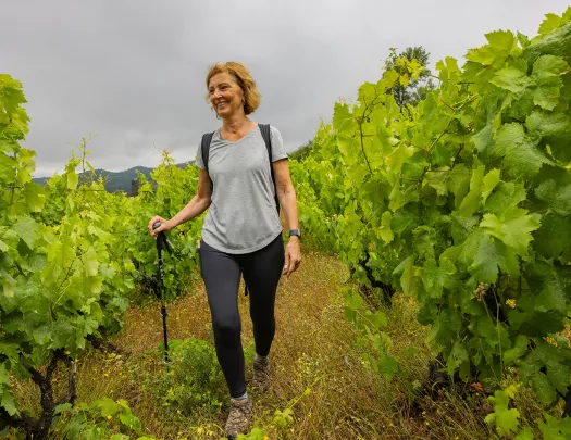 Woman with a walking pole, walking through a field of crops