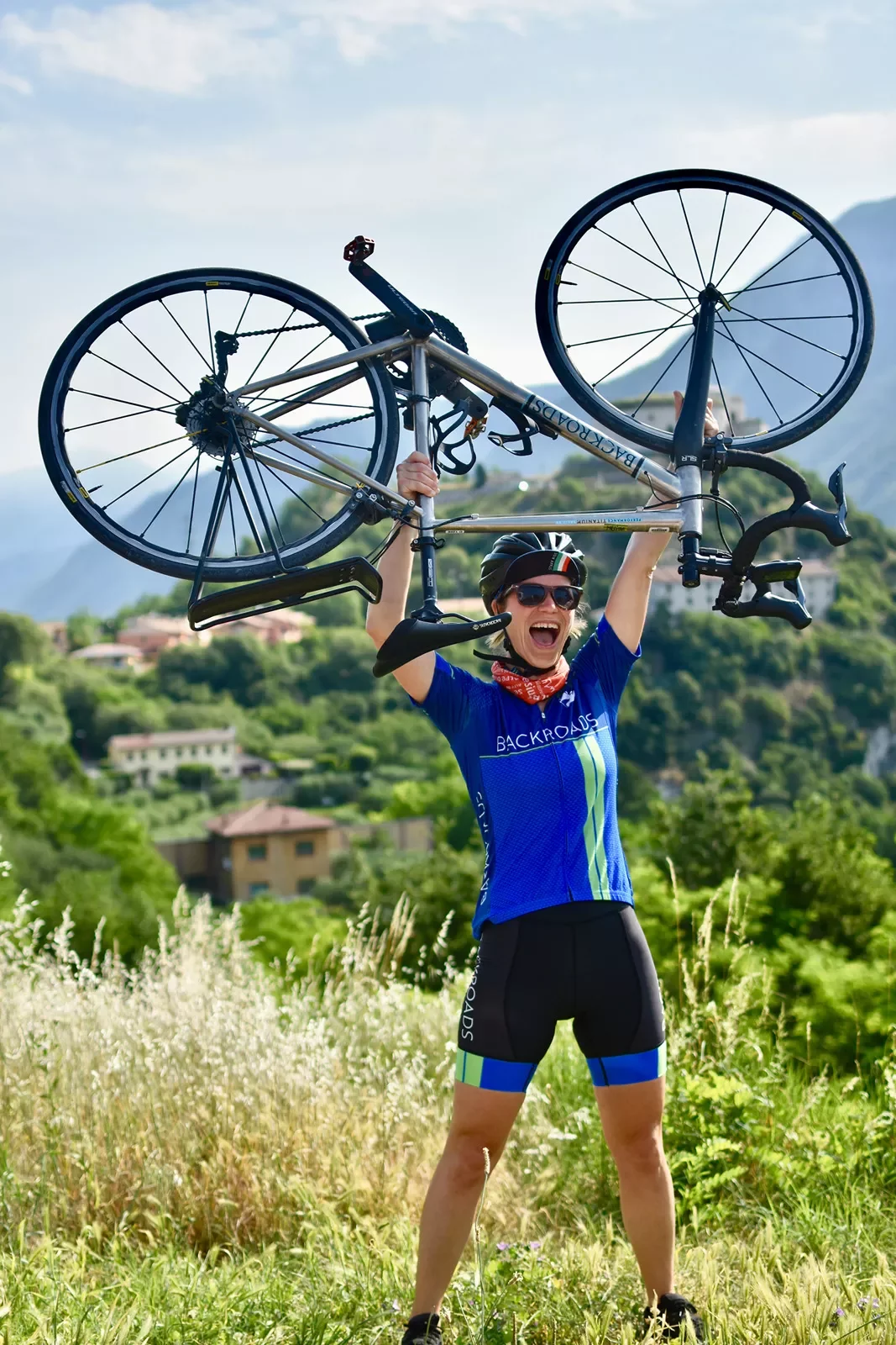 Guest in bike gear, holding bike above her head.