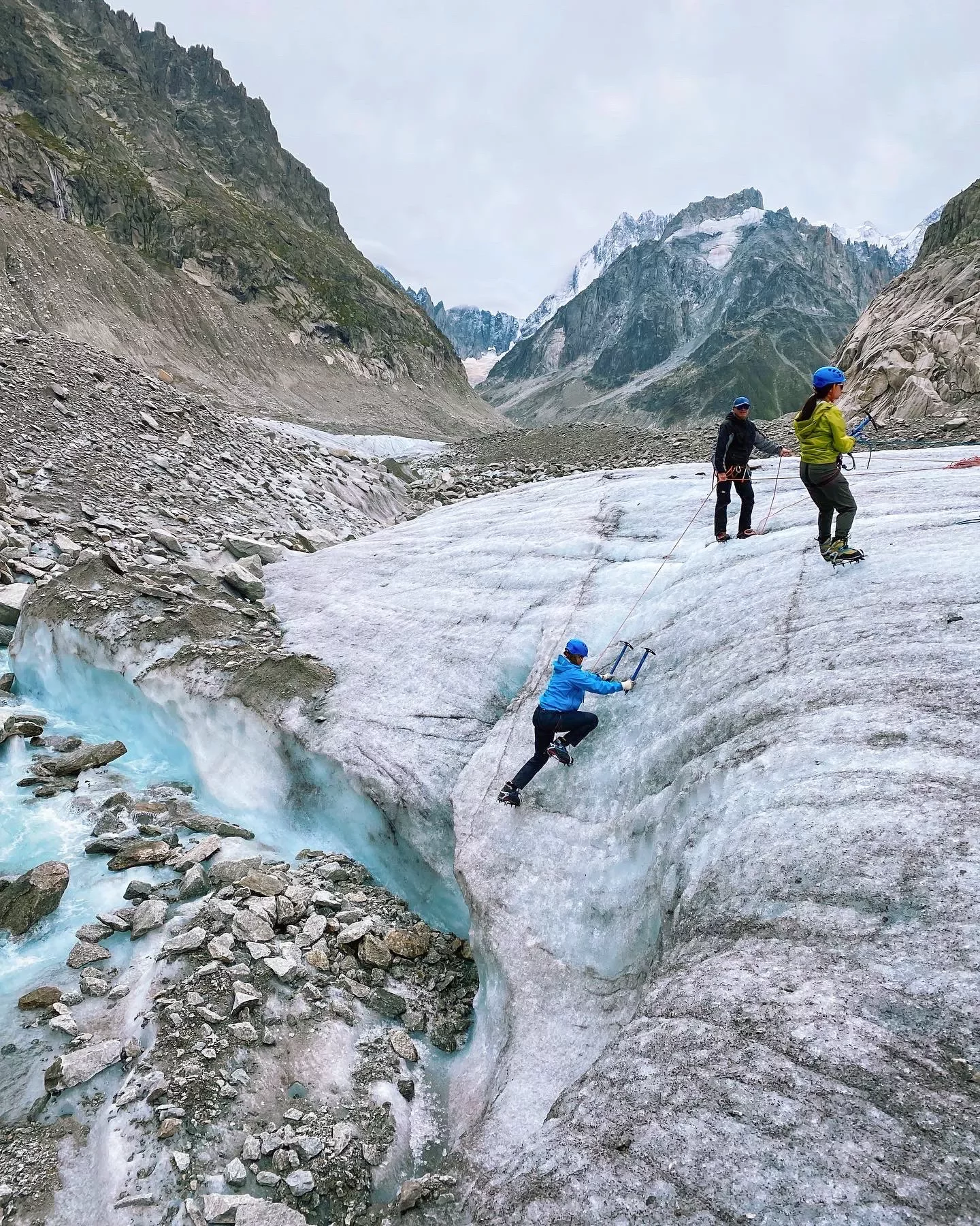 Three guests icepick climbing up icy cliff-face.
