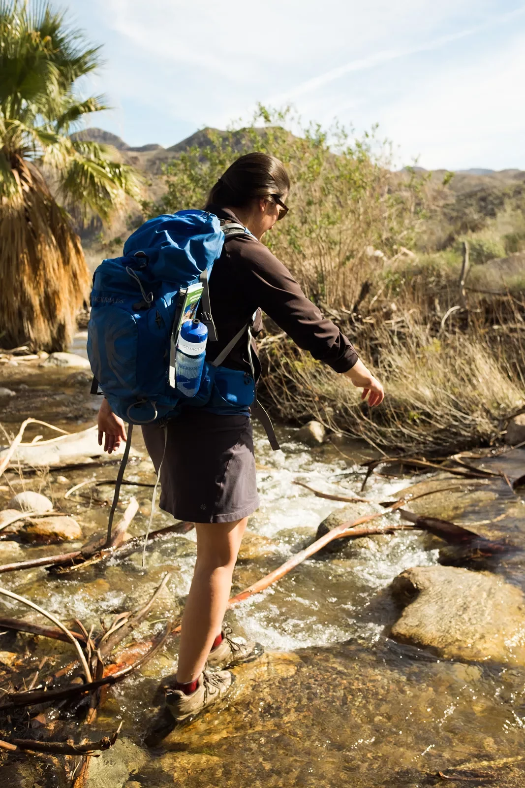 Woman hiker walking through a stream