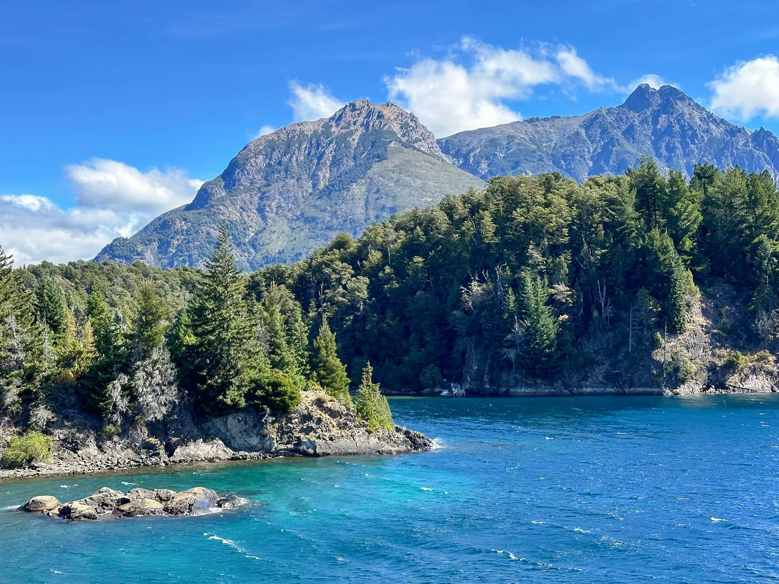 Lake surrounded by large boulders and tall trees