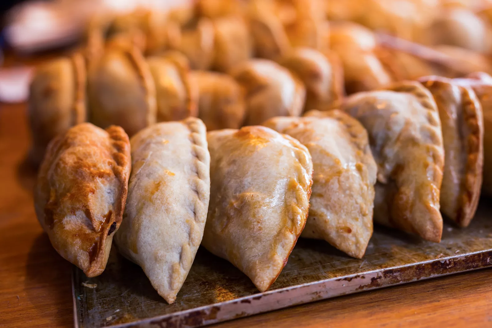 Empanadas lined up on a steel plate