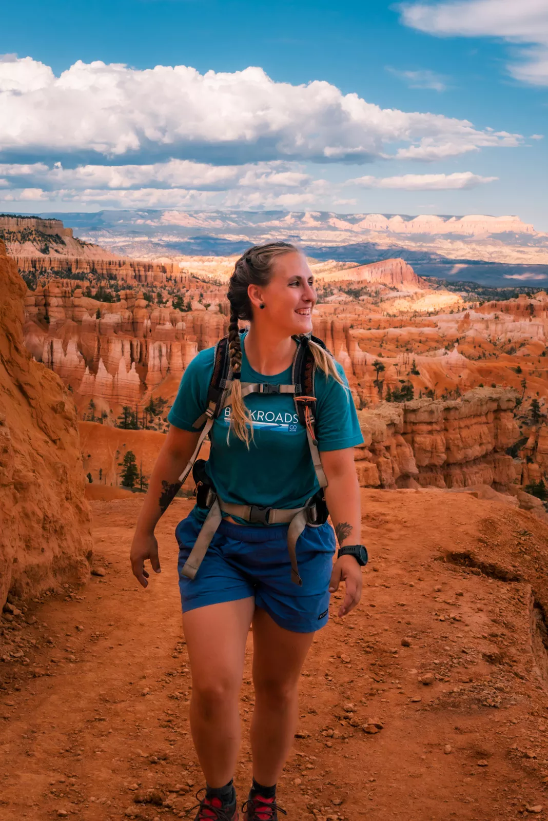 Woman smiling and ascending a red, rocky hill