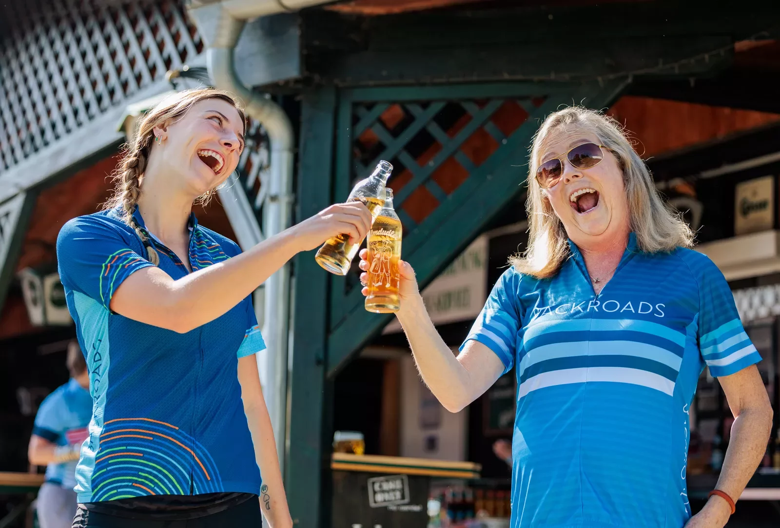 Two woman clinking their bottles of drinks and smiling
