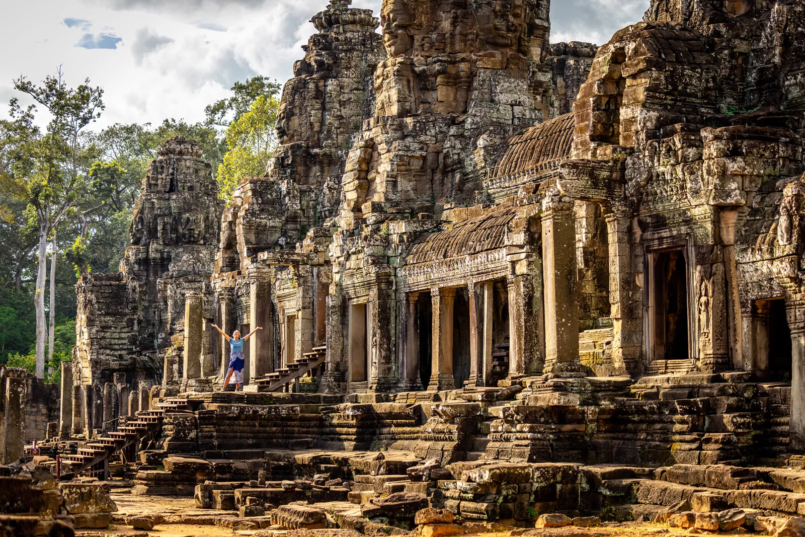 Woman with arms open next to ancient temple ruins