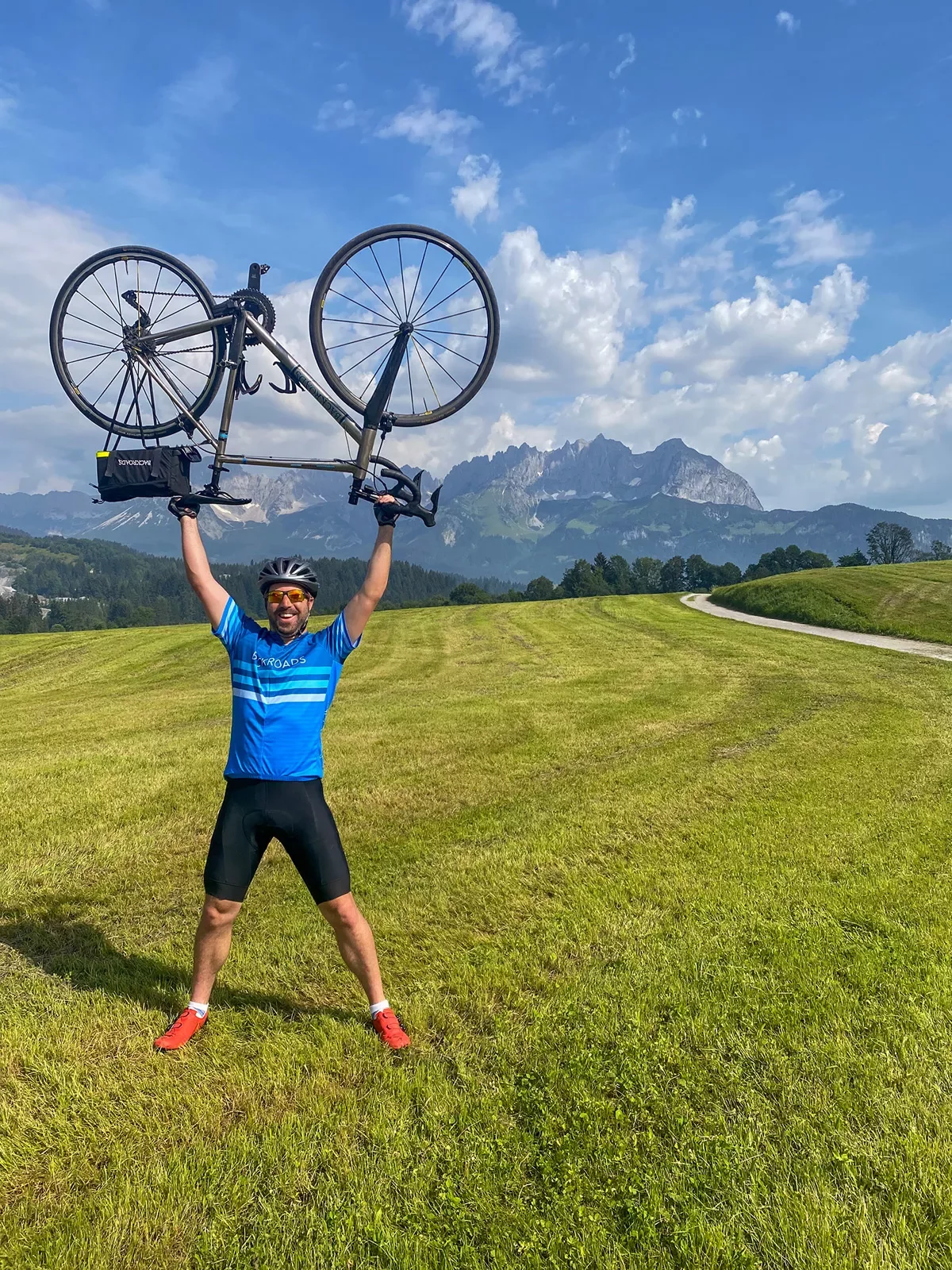 Man in a grassy field holding up a bike over his head