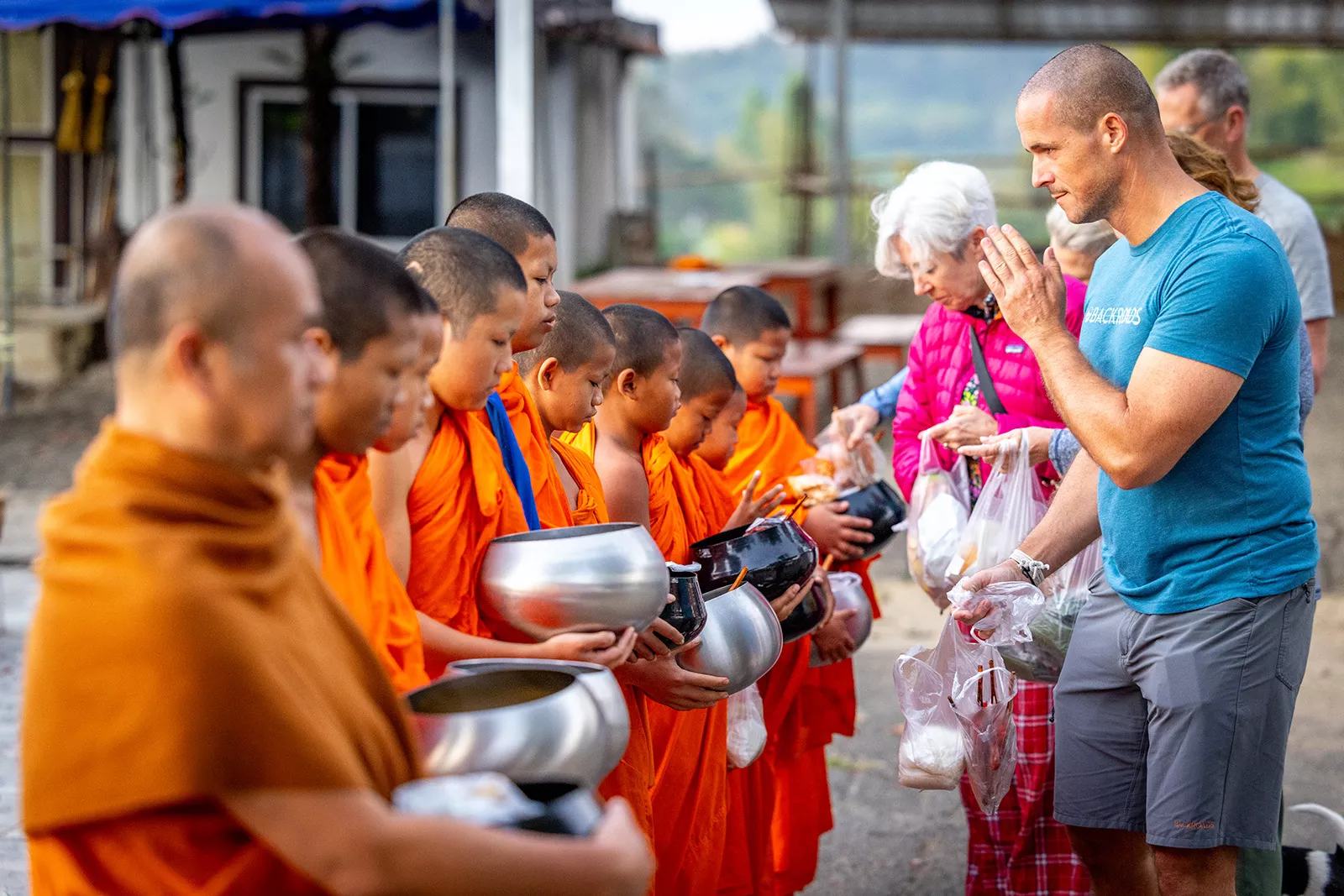 Group of people praying in front of monks with orange robes