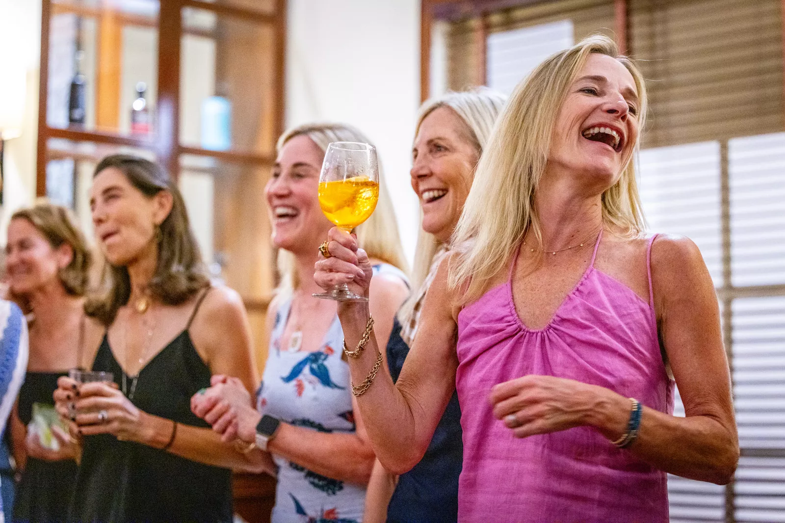 Group of women holding wine glasses and laughing