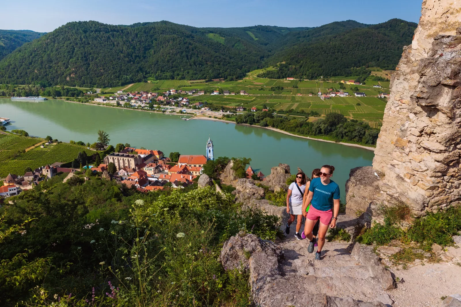 Three women hiking cliffside overlooking the water