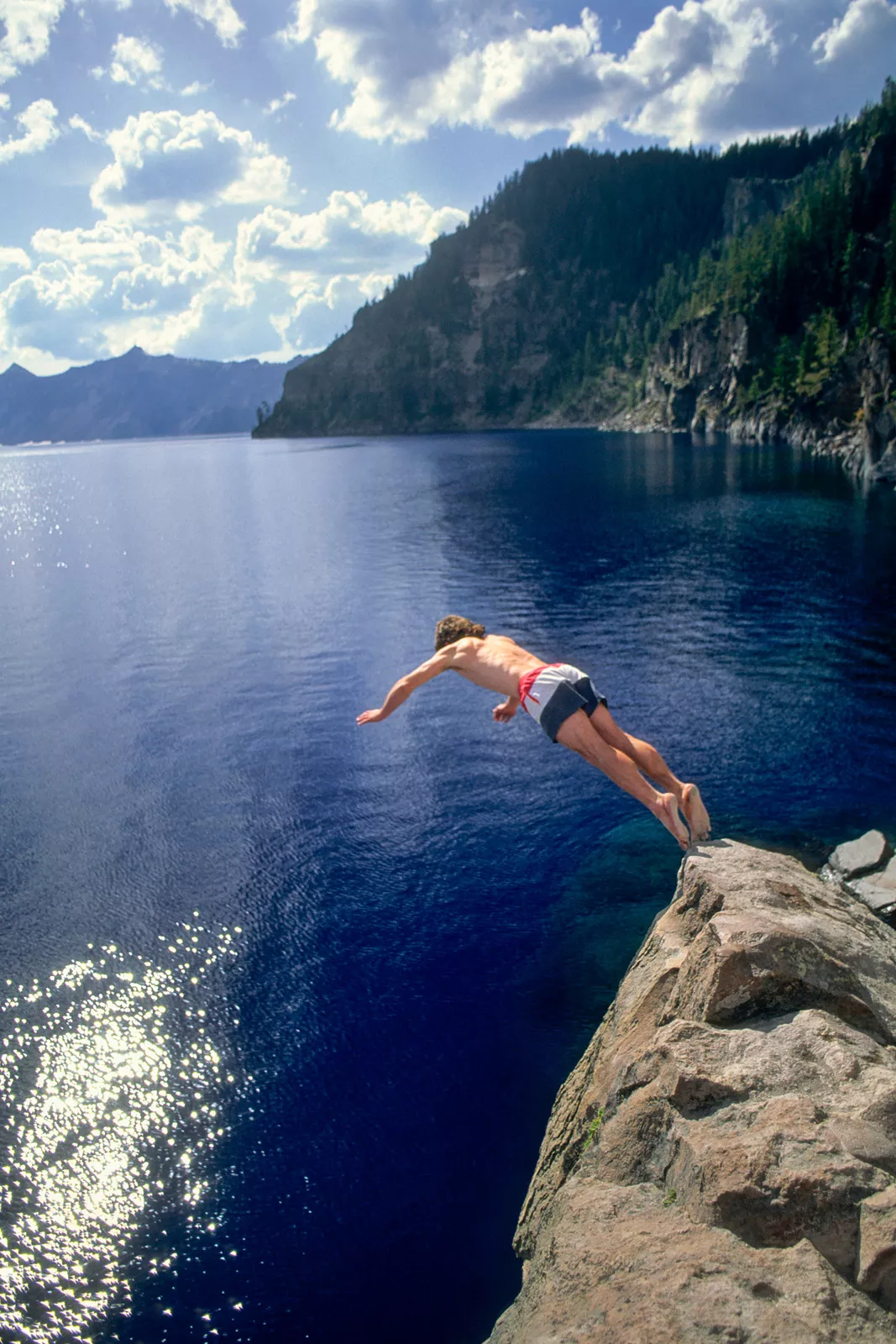 Man jumping of a cliff into a lake