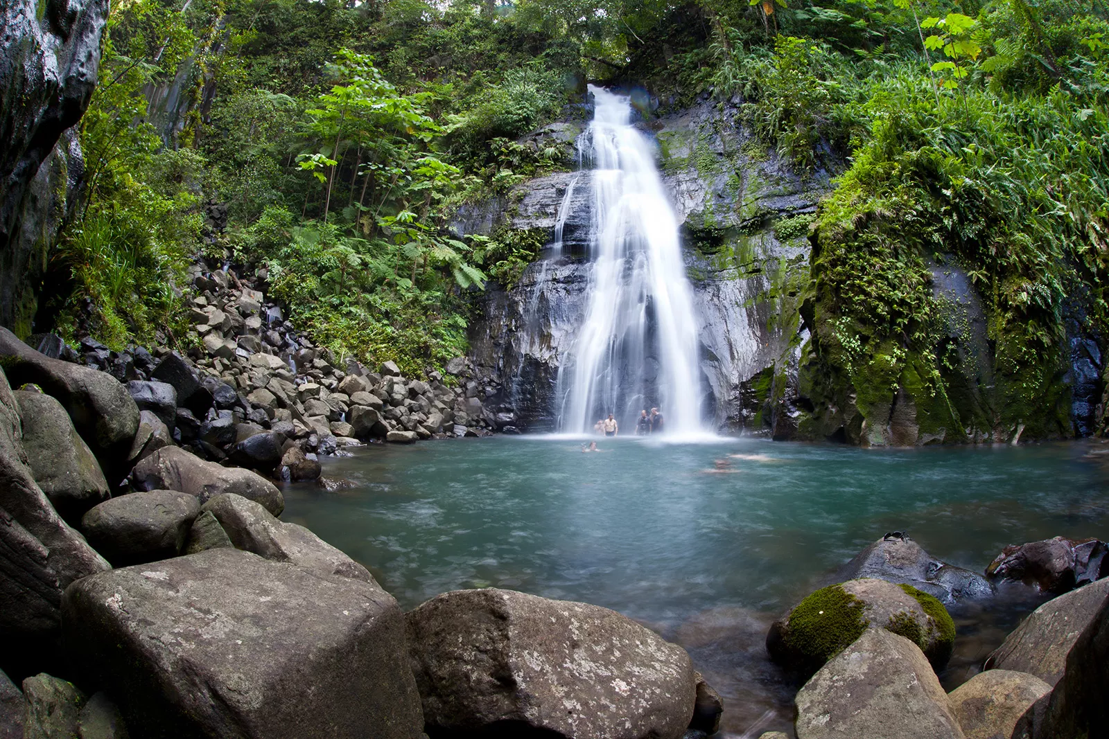 Group of people under a waterfall in a lake