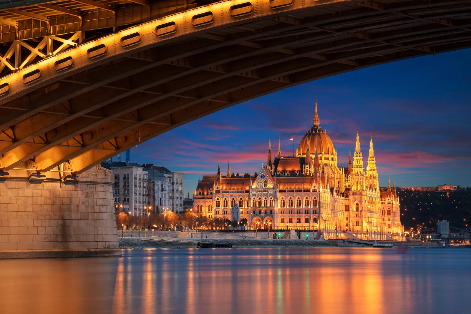 Under-bridge view of an illuminated, castle-like building in the distance