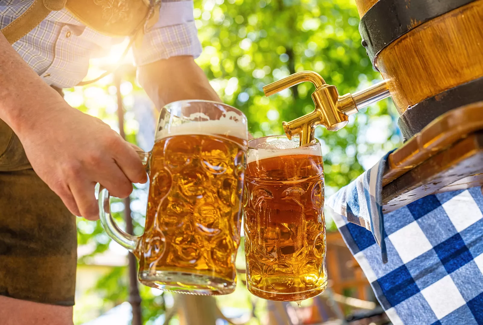 Person filling two mugs with beer