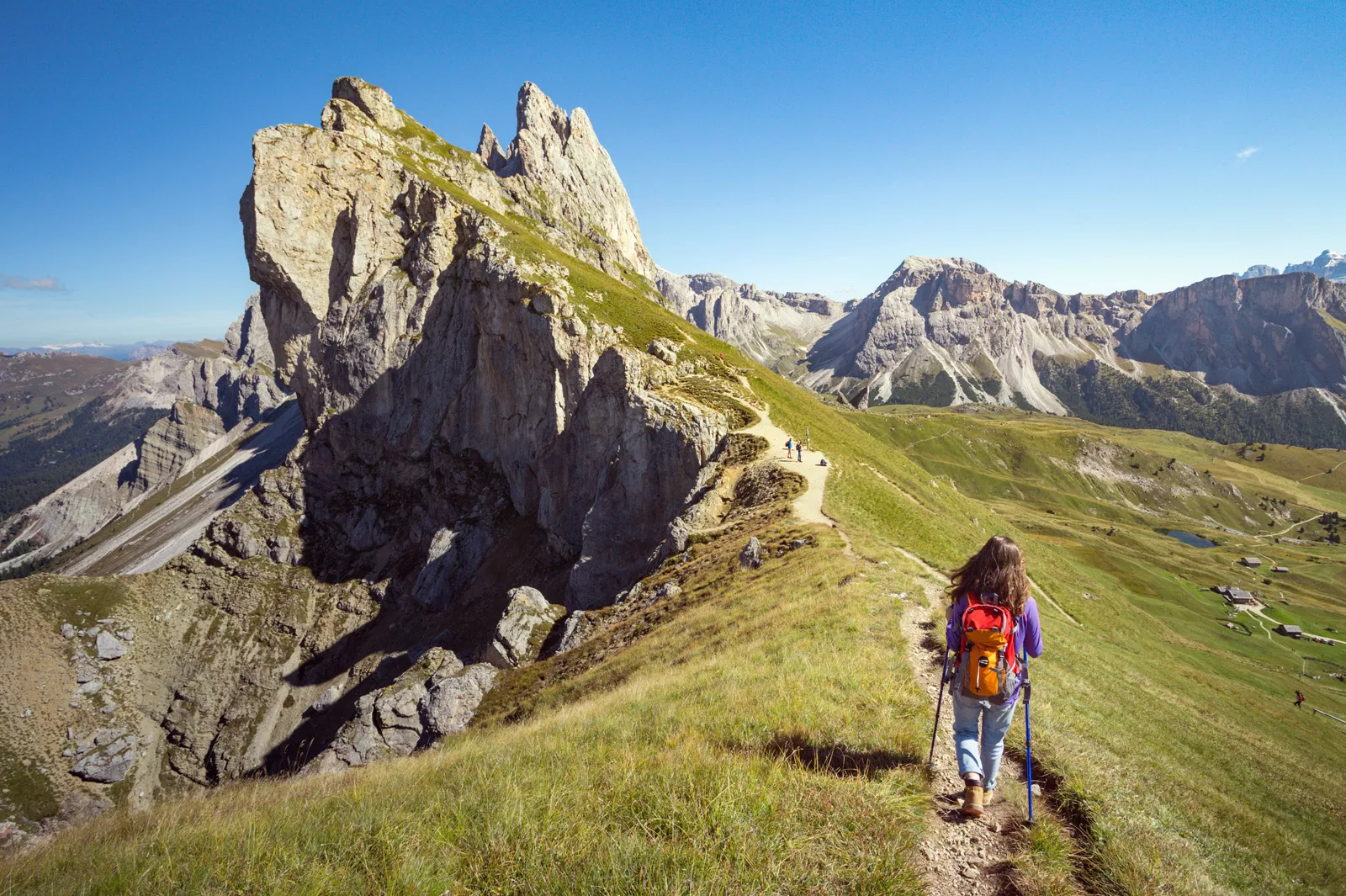 Woman hiking on a dirt trail towards the edge of a cliff