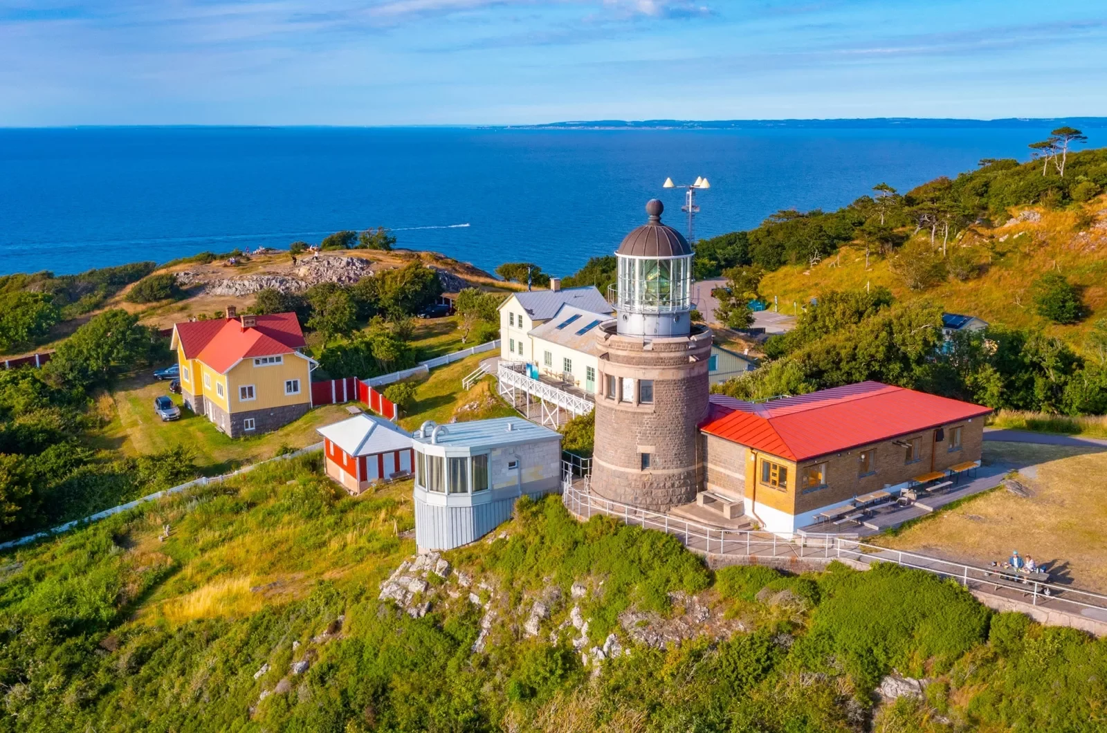 Lighthouse building with smaller buildings and the ocean in the distance