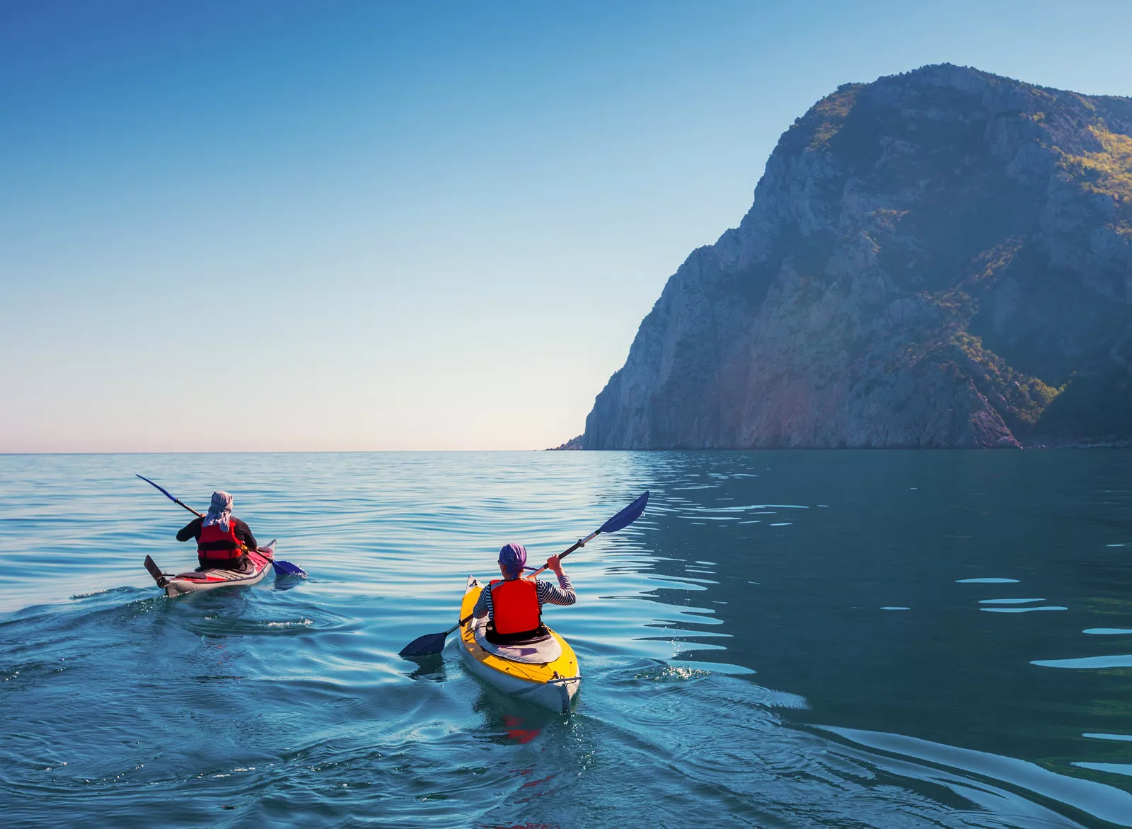 Two people paddling on kayaks in the middle of the ocean