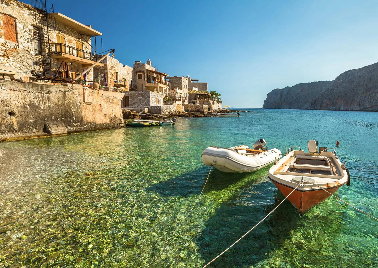 Two small boats tied to a dock with rustic buildings in the background