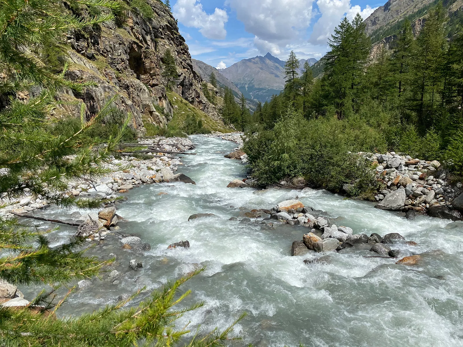 Active river filled with rocks, surrounded by two tall mountains