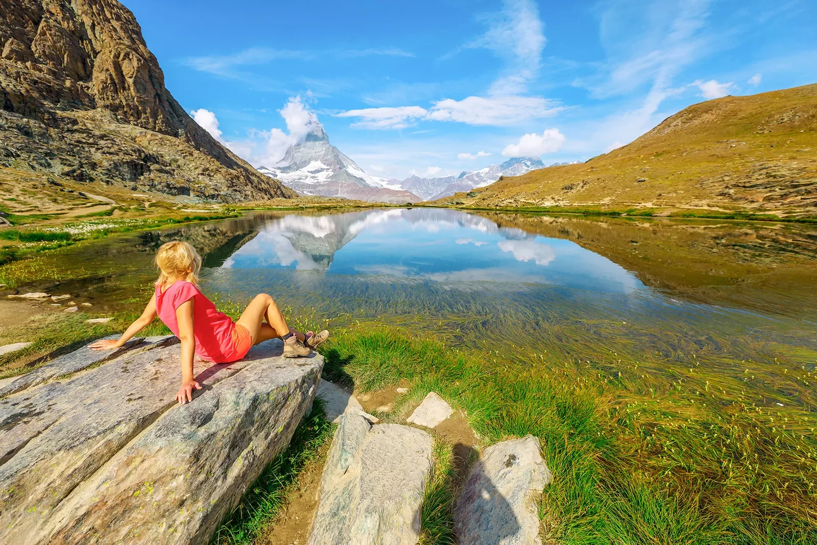 Girl sitting on a rock looking out to a lake and valleys