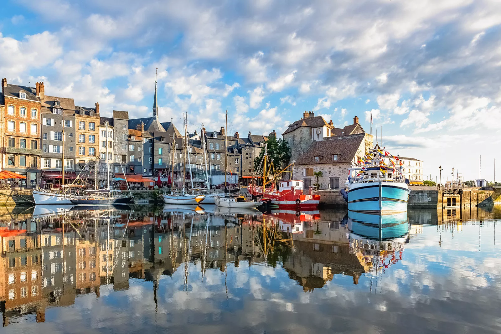 Port of boats on the water, next to a row of tall, stone buildings