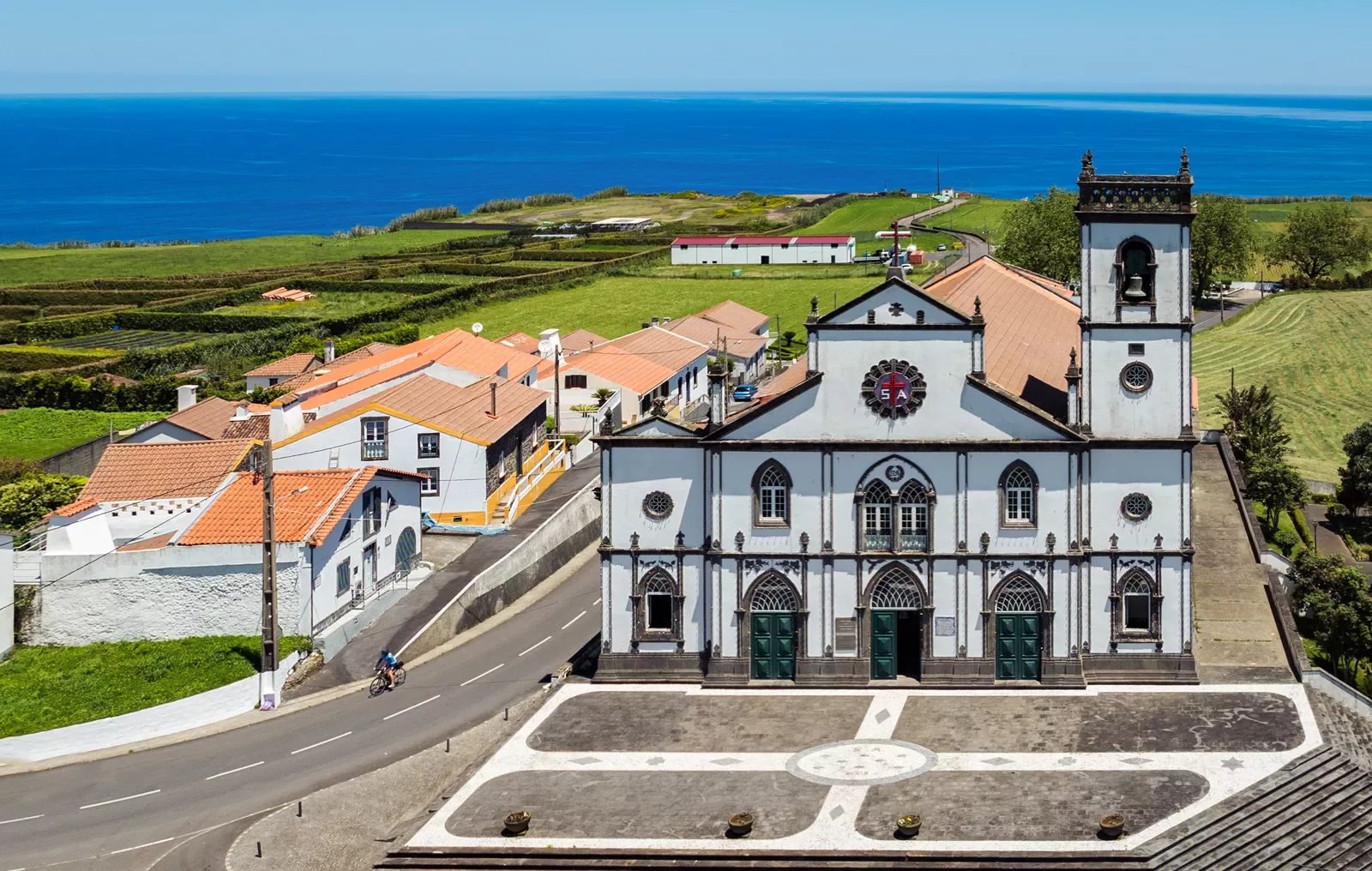 Large church building in the middle of a small town, with an ocean in the background