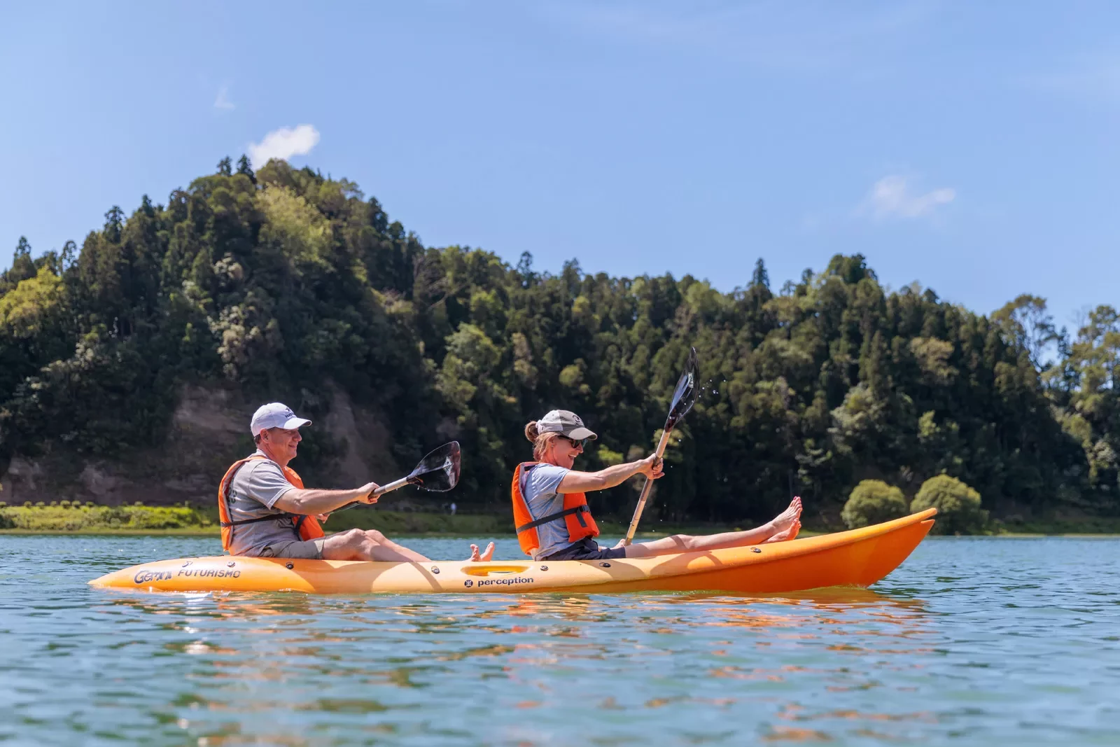 Man and woman inside of a kayak, paddling in the middle of a lake