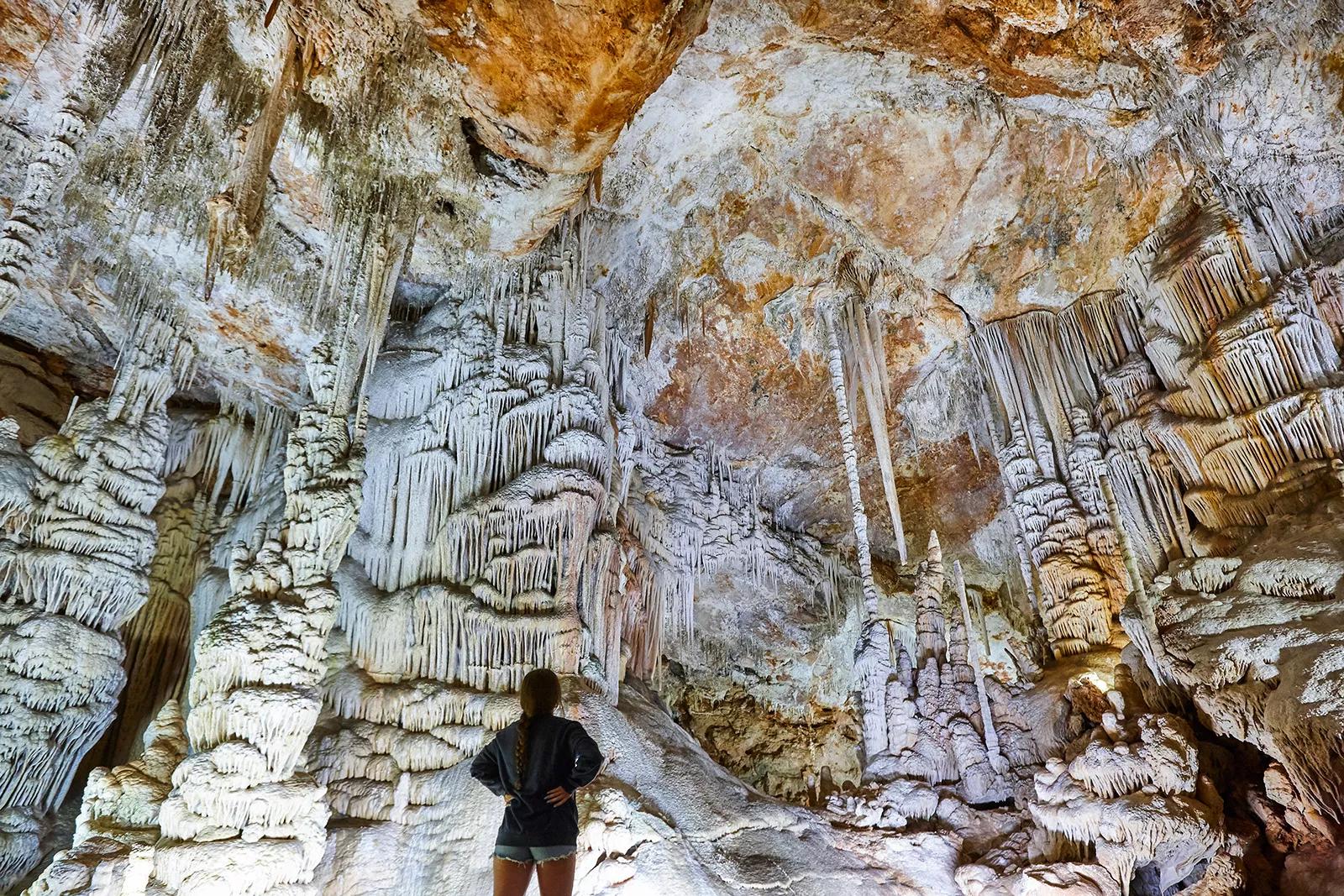 Woman looking up at a white and orange cave