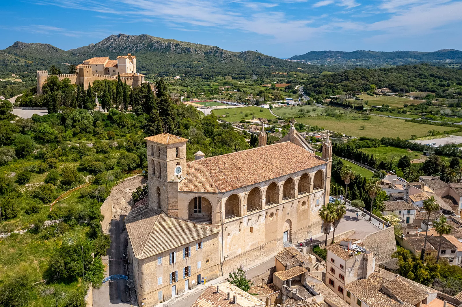 Top view of stone, yellow building with archways and trees behind the building