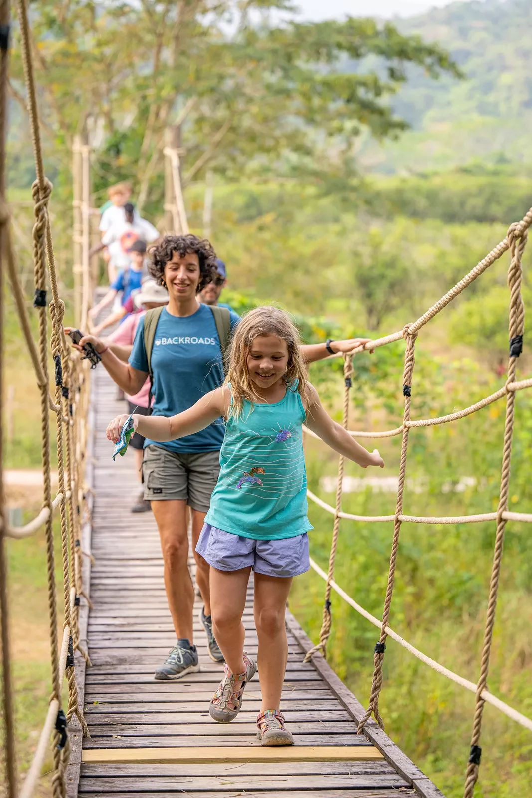 Group of hikers and children on a wooden rope bridge