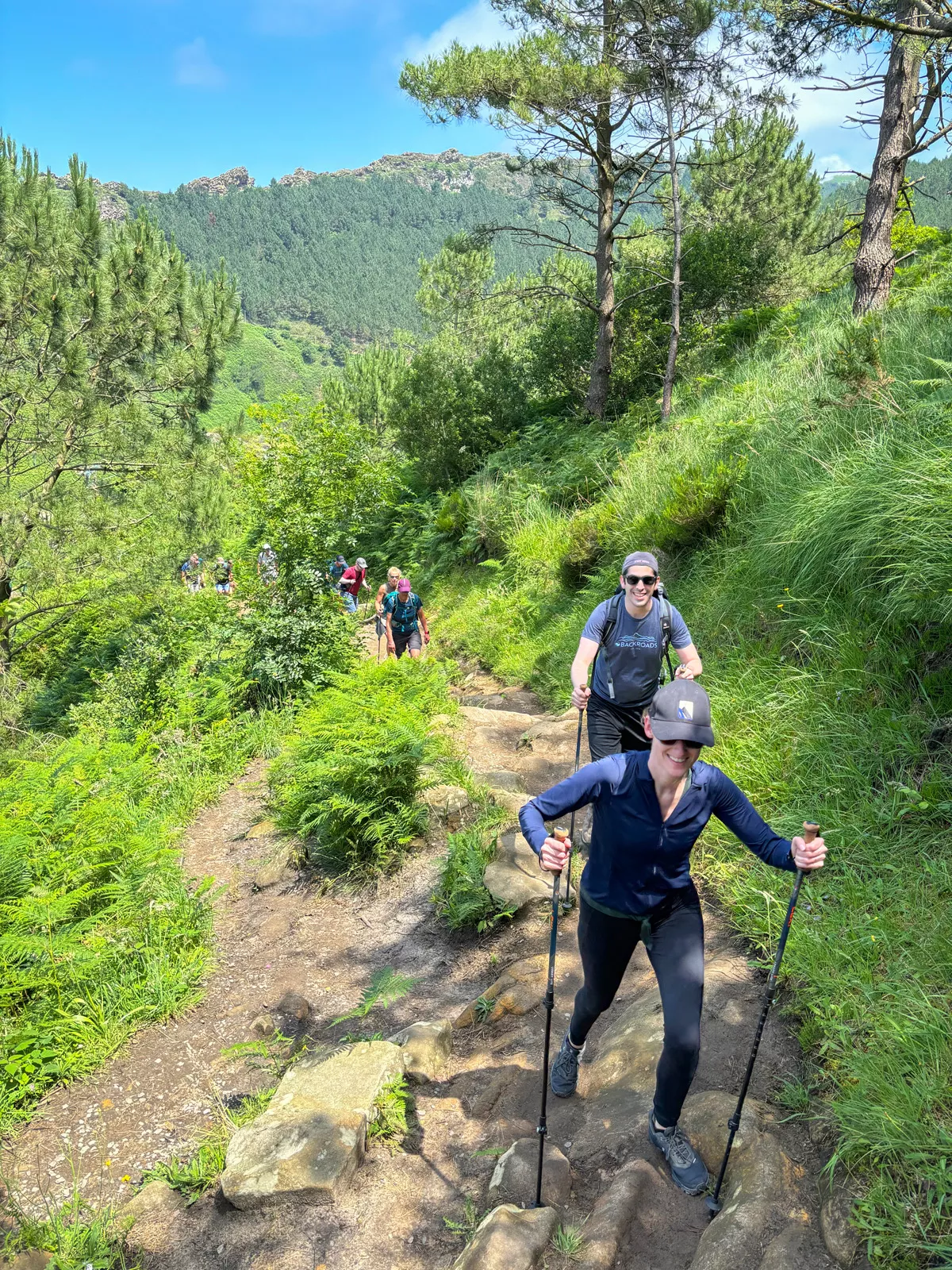 Group of hikers with walking poles ascending up a rocky trail