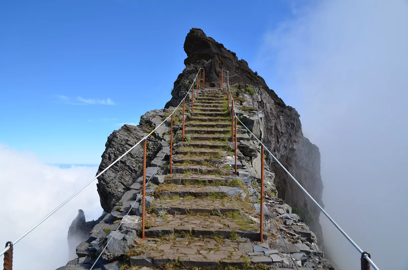 Stone stair way with metal railings leading towards the peak of a mountain