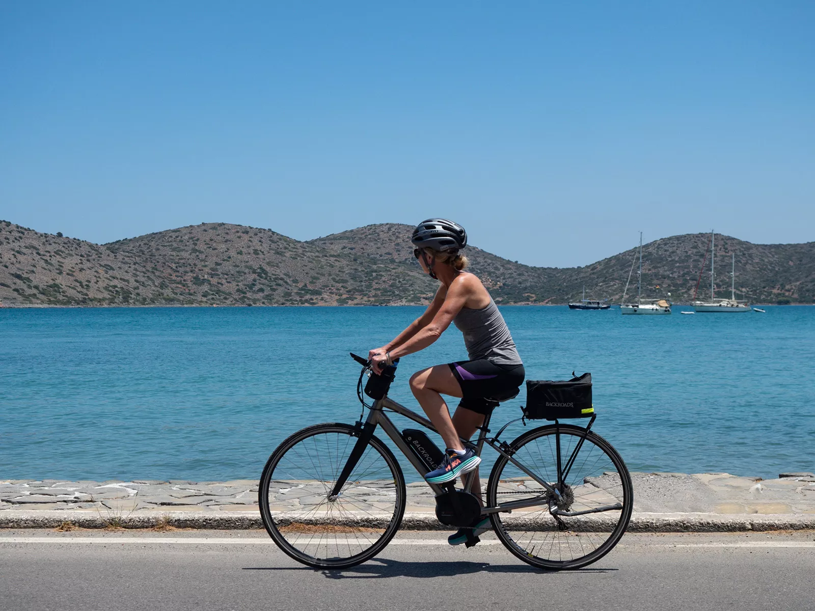 Woman on an e-bike along a road next to the ocean