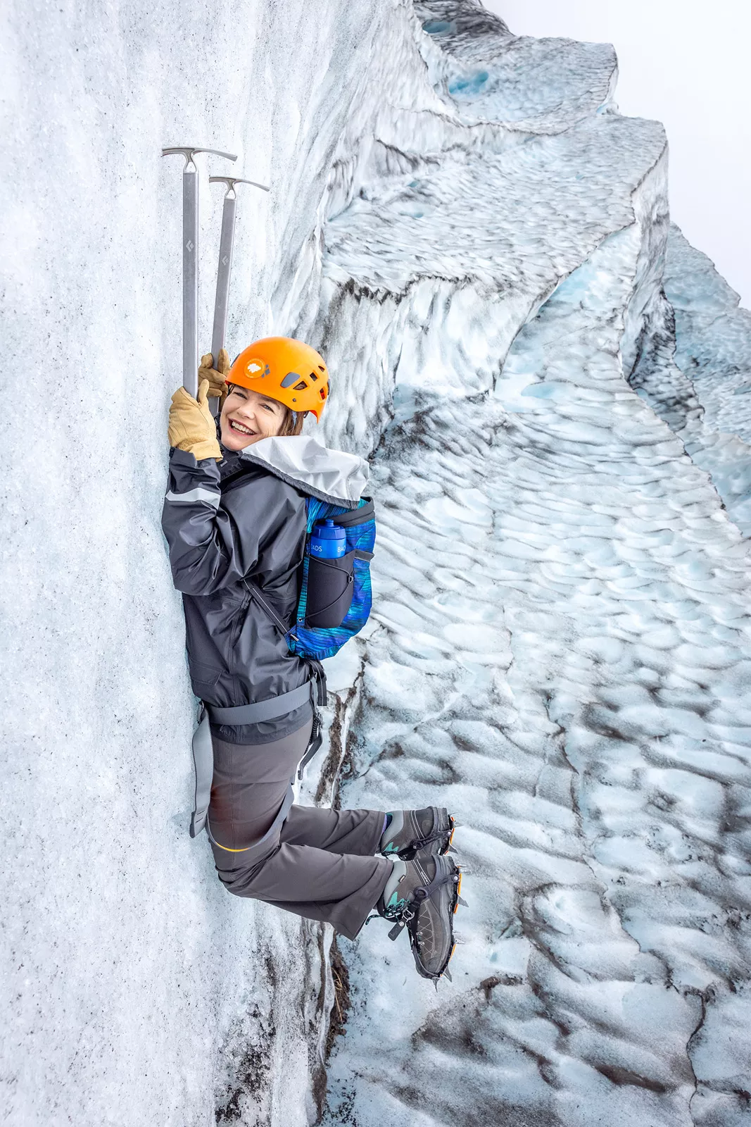 Woman hanging on to two sickles in a snowing mountain