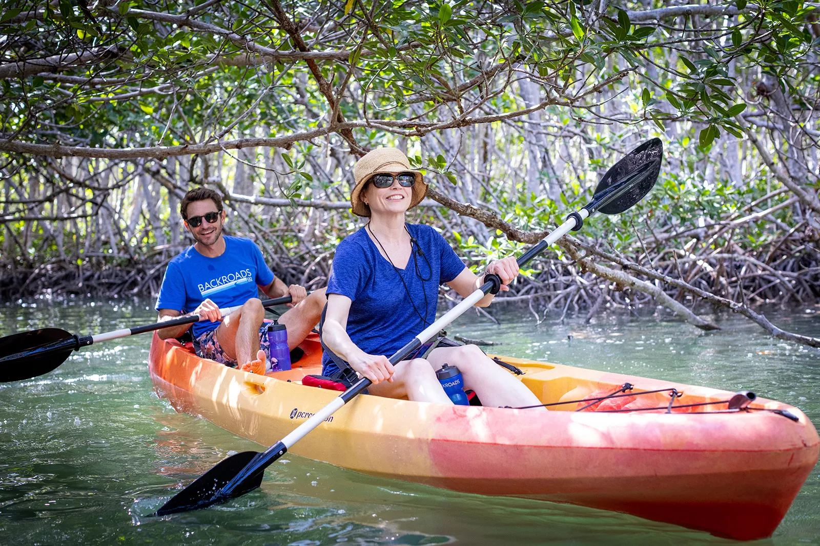 Man and woman paddling on a red and yellow kayak