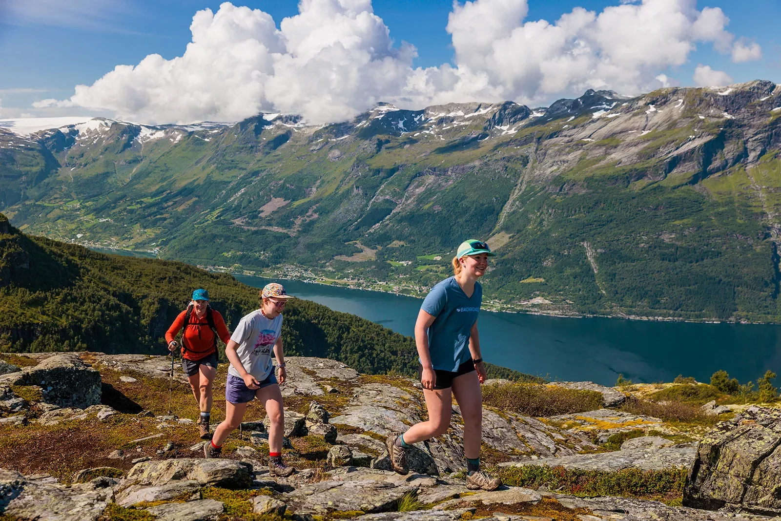 Three women ascending a stone path with mountains in the distance