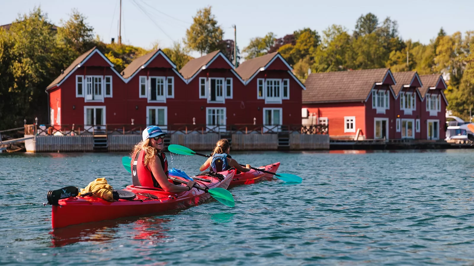 Two woman in kayaks paddling toward a dock