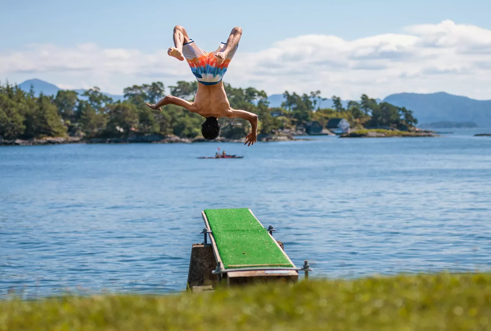 Man backflipping from the ledge into a lake