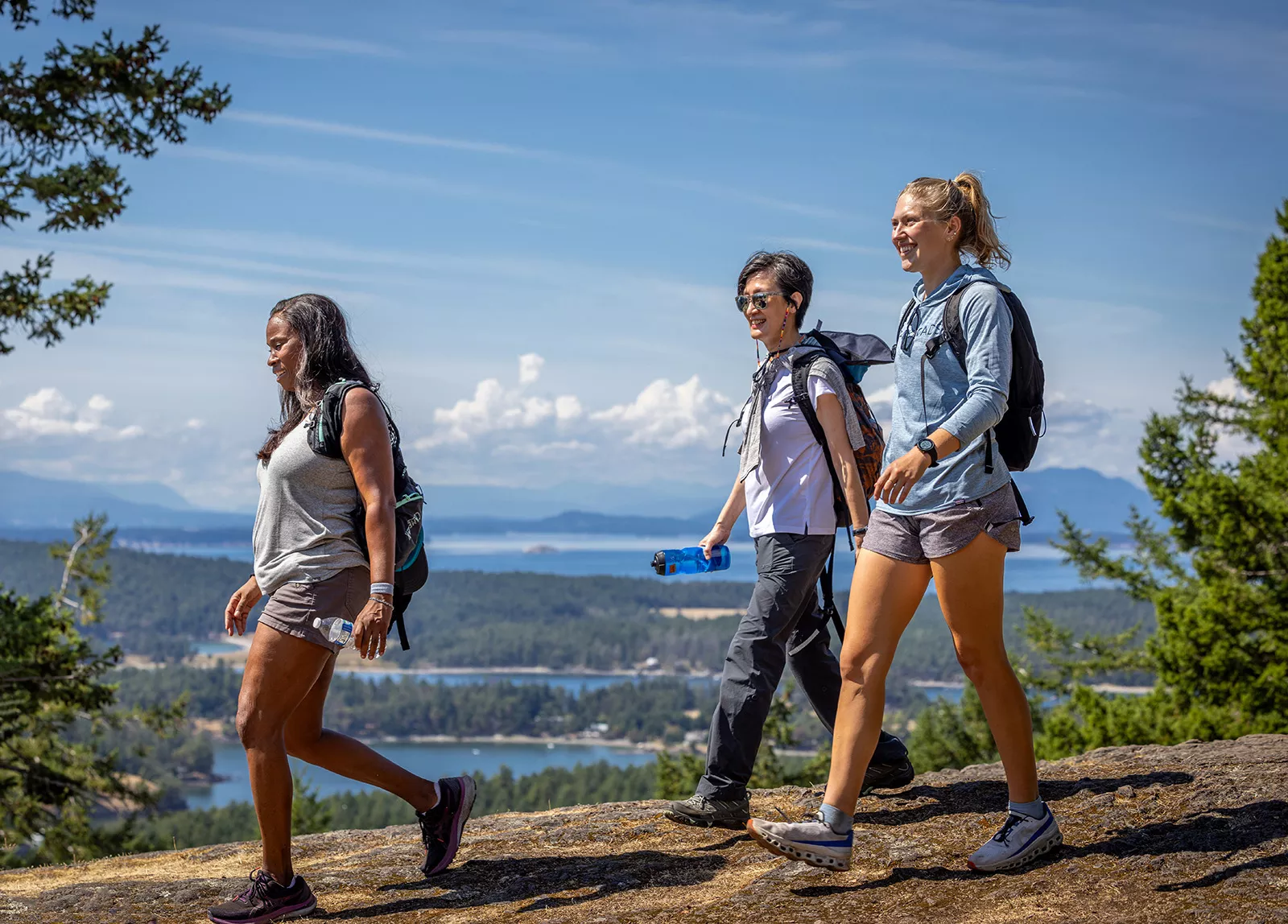 Group of three women hiking down a dirt path on a hill