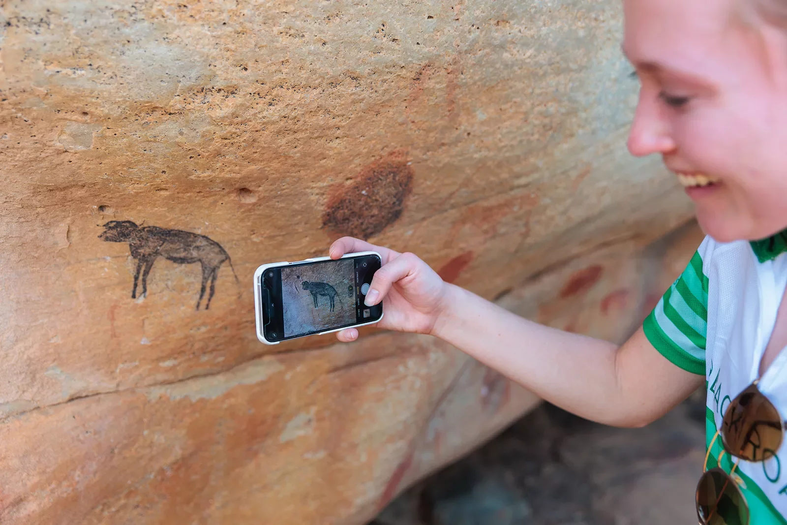 A person takes a photo of cave drawings