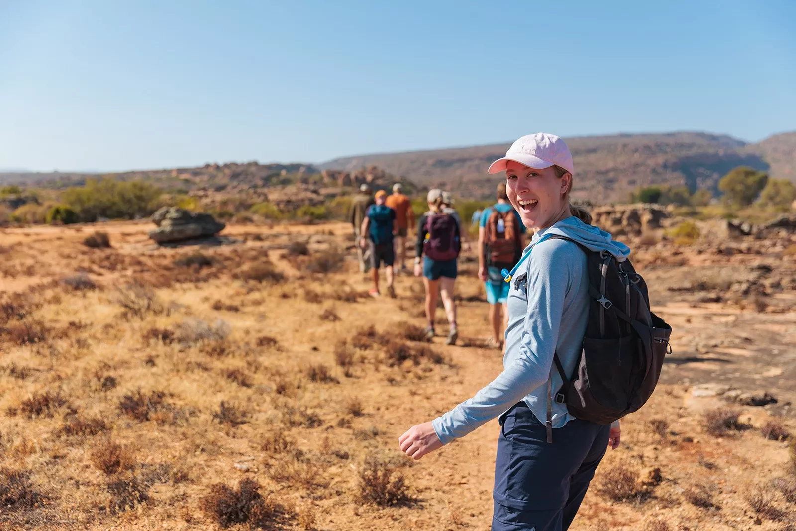 A group of hikers walk through a sandy field