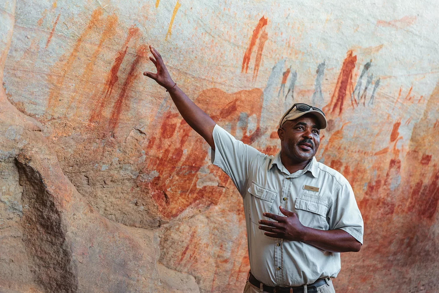 A man points to cave paintings on a wall