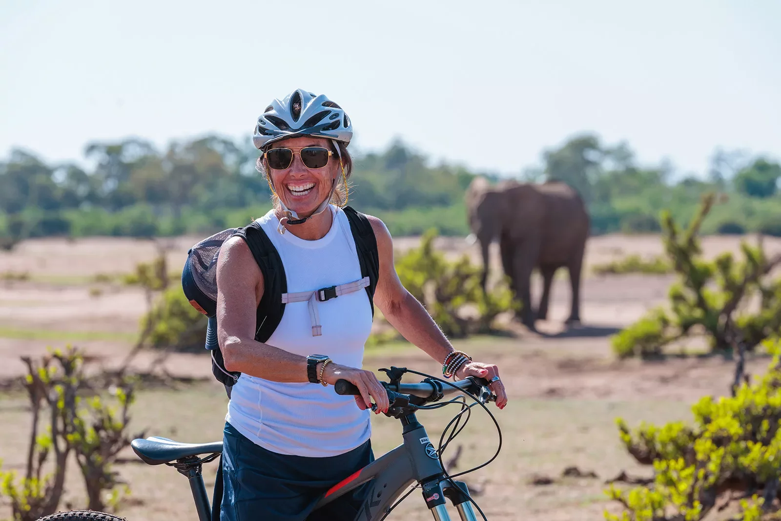 A person with a bike poses in front of an elephant
