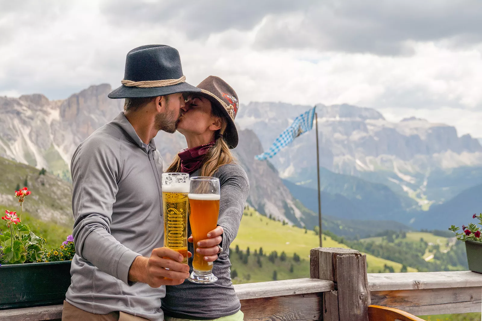 Man and woman kissing while holding up glasses of beer