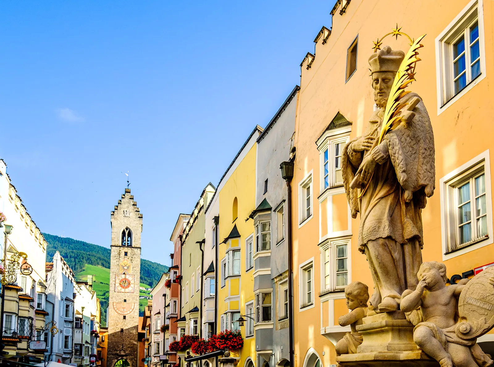 Spanish-style statue in a town center with a clocktower in the background