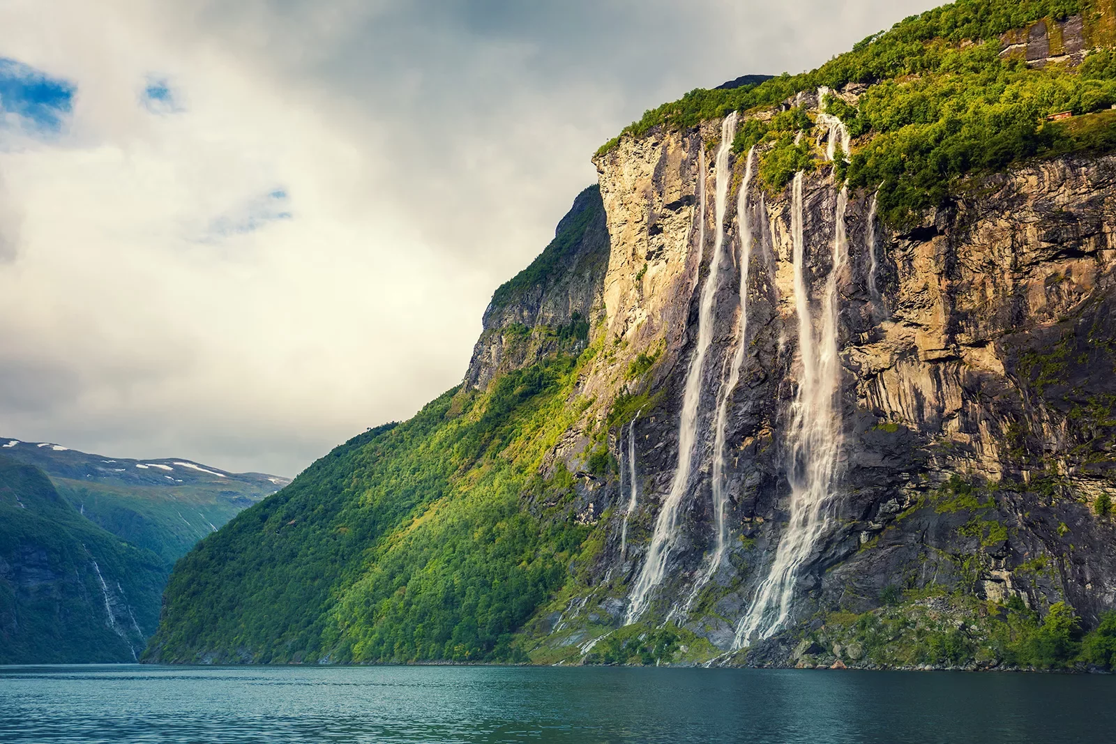 Cliff covered in trees with a waterfall in between